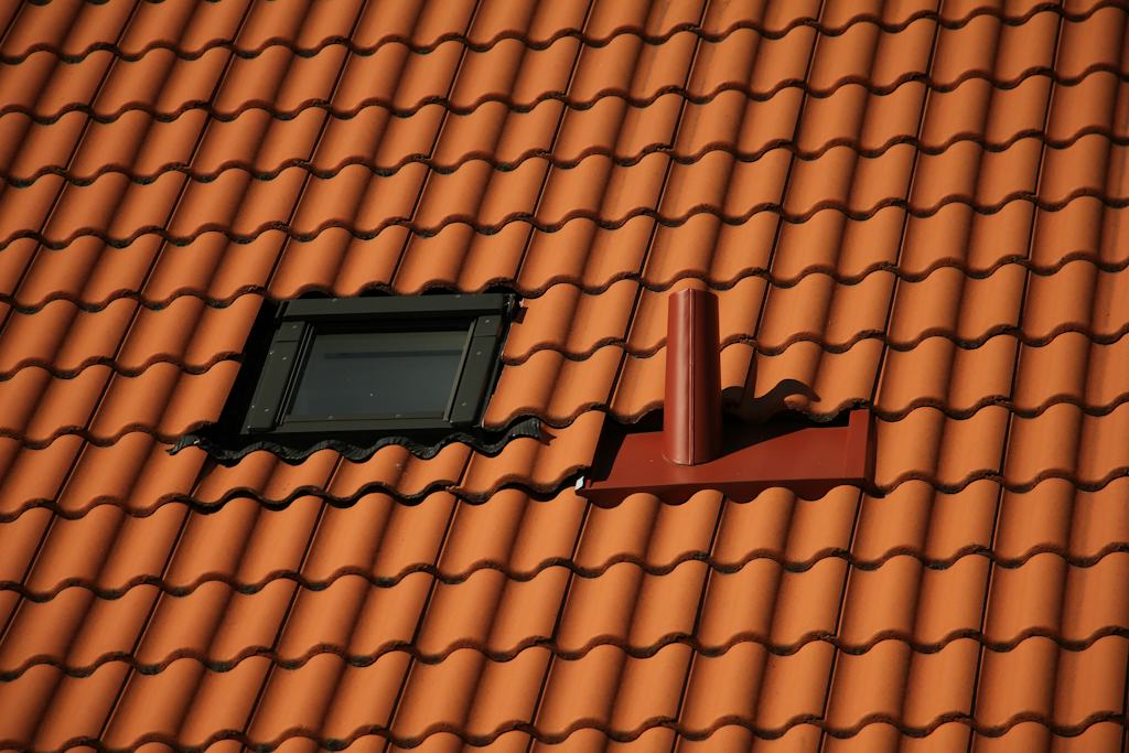 Clay tile roof with a skylight and a vent pipe flashed into the tiles